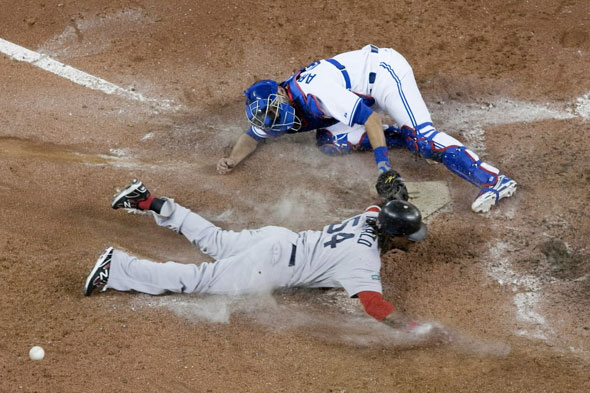 Boston Red Sox's Darnell McDonald slides into home plate to score against Toronto Blue Jays catcher J.P Arencibia during the ninth inning of a baseball game in Toronto on Monday, April 9, 2012. Boston won 4-2.