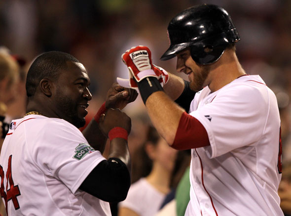 Boston Red Sox third baseman Will Middlebrooks is congratulated in the Sox dugout by Boston Red Sox designated hitter David Ortiz after his two run homer in the eighth inning.  The Boston Red Sox took on the Miami Marlins at Fenway Park.