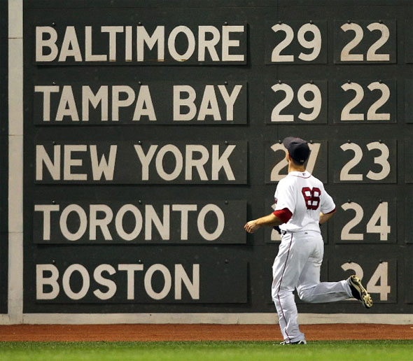 Red Sox left fielder Daniel Nava watches an 8th inning homer by Tigers Delmon Young, as the standing are seen on the scoreboard.
