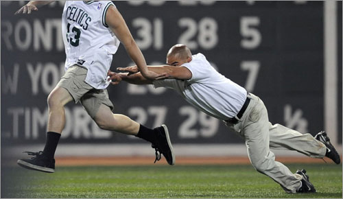 A fan running on the field avoids getting tackled during the eighth inning as the Boston Red Sox take on the Tampa Bay Rays on June 3, 2008 at Fenway Park in Boston, Massachusetts.