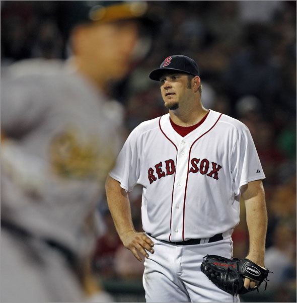 Red Sox starting pitcher Brad Penny looks upset as the A's Mark Ellis (foreground left) rounds first as the ball he hit to lead off the sixth inning bounces into the right field stands for a ground rule double. Penny would be pulled from the game afer the hit.