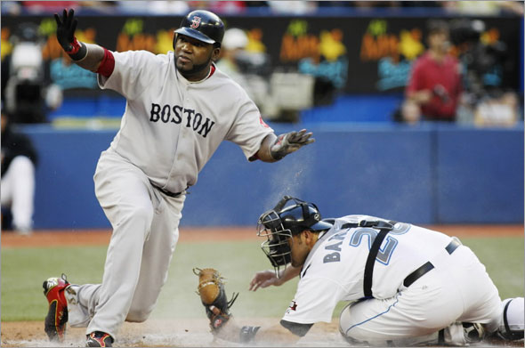 Red Sox David Ortiz waves safe after sliding into home safely as Toronto Blue Jays Rod Barajas tries to tag him during the second inning of their MLB American League baseball game in Toronto August 18, 2009.