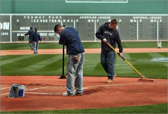 The season opener at Fenway Park might be a washout on Monday, but groundscrew members John Driscoll pounds down the dirt around homeplate while Jeremy Fuller smooths the gravel in the the area on Saturday morning. 