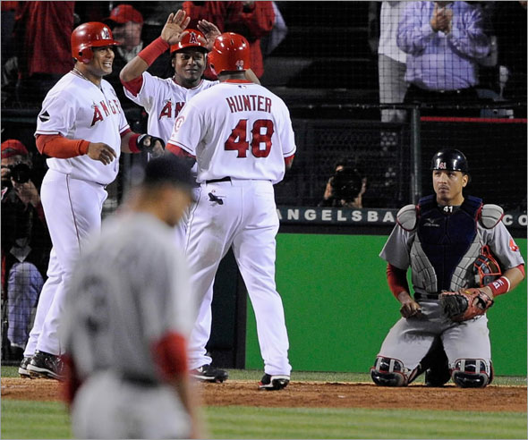 Torii Hunter of the Los Angeles Angels of Anaheim celebrates with teammates after hitting a three-run home run as starting pitcher Jon Lester #31 and catcher Victor Martinez #41 of the Boston Red Sox look on in the fifth inning of Game One of the ALDS during the 2009 MLB Playoffs at Angel Stadium