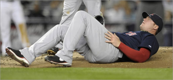 Red Sox starting pitcher Jon Lester rolls on the mound after he was hit by a ball off the bat of New York Yankees batter Melky Cabrera in the third inning of their MLB American League baseball game at Yankee Stadium in New York