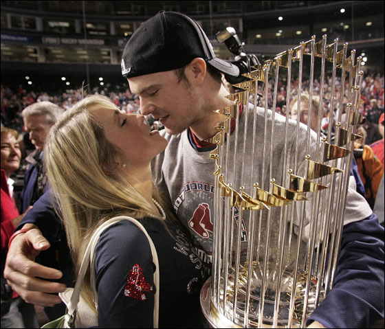 Winning pitcher Jon Lester kisses his girlfriend Farah Johnson as he holds the World Series trophy.