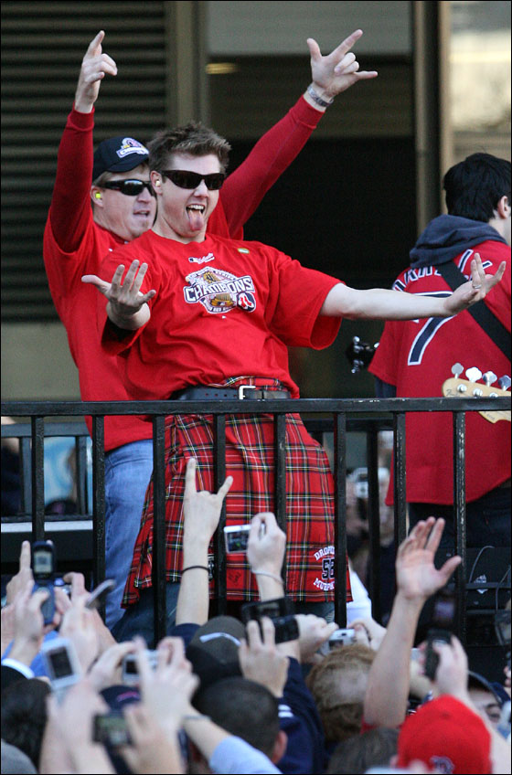 Boston Red Sox players Jonathan Papelbon (foreground, right) and Mike Timlin (behind left) celebrate the team's World Series championship on flatbed truck as rolling rally passes Boston City Hall.