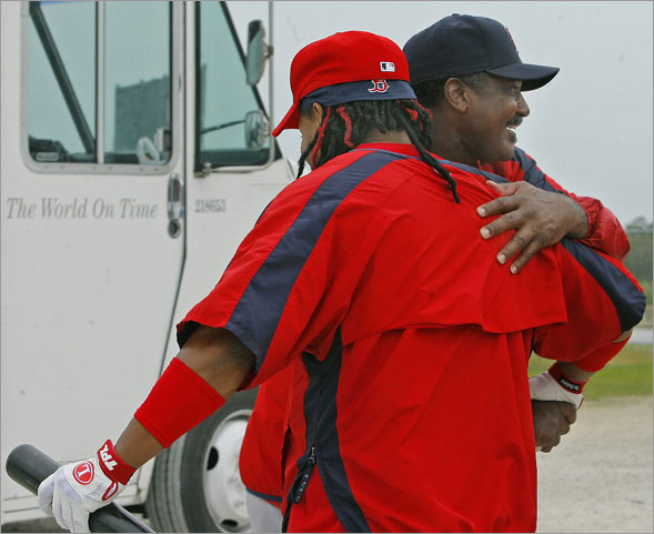 An ironic phrase is seen in the backround at left on a FedEx truck that just happened to be driving by as Red Sox leftfielder Manny Ramirez, (left), gets a hug from another legendary Boston leftfielder, Jim Rice (right)