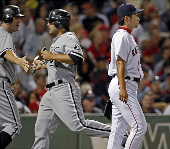 Red Sox starting pitcher Junichi Tazawa (who was backing up the plate) doesn't join in the hand slapping of the White Sox Jim Thome (left) and Carlos Quentin (center) who have both just scored on a wall scraping double by number nine hitting teammate Jayson Nix in the second inning.