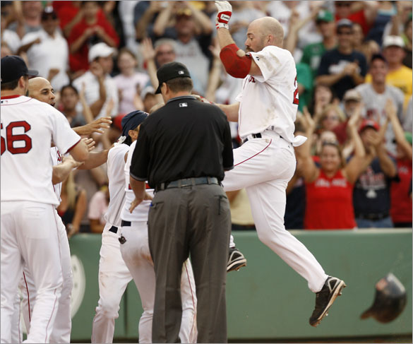 Red Sox's Kevin Youkilis jumps into his teammates waiting at home plate after his two-run walk off home run during the bottom of the 13th inning of their 5-3 win over the St. Louis Cardinals in a baseball game at Fenway Park in Boston, Sunday, June 22,  2008