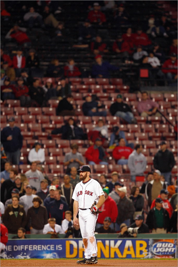 Kevin Youkilis #20 of the Boston Red Sox looks on as the stands are seen nearly empty during game four of the American League Championship Series against the Tampa Bay Rays during the 2008 MLB playoffs at Fenway Park on October 14, 2008 in Boston, Massachusetts. 