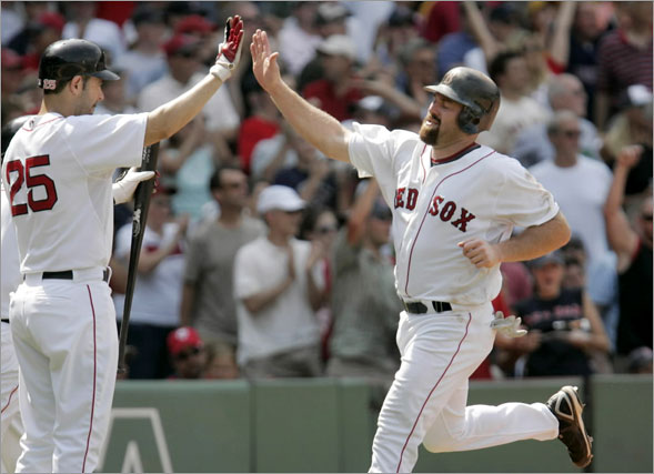 Kevin Youkilis, right, is welcomed to home plate by Mike Lowell as Youkilis scores on a double by Manny Ramirez in the fifth inning of a baseball game against the Minnesota Twins at Fenway Park in Boston on Wednesday, July 9, 2008