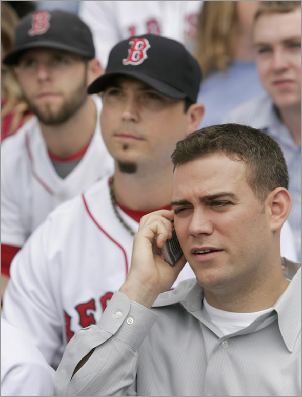 Red Sox general manager Theo Epstein, front right, speaks on a cell phone as Red Sox pitcher Josh Beckett looks on during a team photo shoot at Fenway Park.