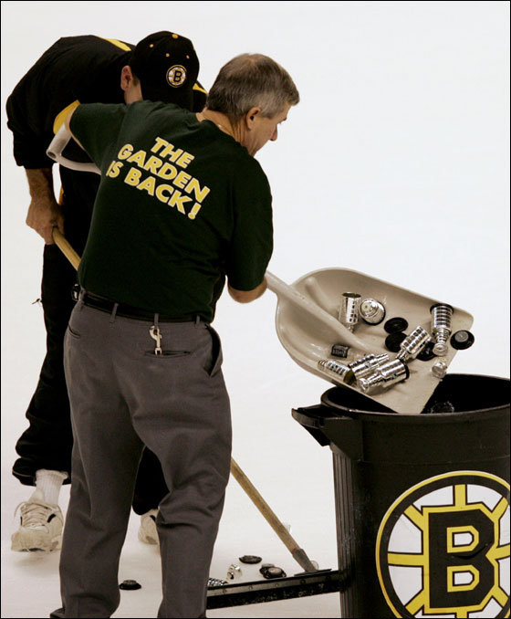 Workers clear mini replicas of the Stanley Cup, a fan appreciation gift, which were thrown on the ice by fans following a Montreal Canadiens goal in the final minute of a game against the Boston Bruins in Boston, Wednesday Oct. 5, 2005.  The Canadiens beat the Bruins 2-1.