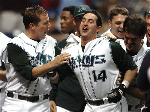 Devil Rays Shawn Camp, left, Jorge Cantu, right, and other teammates mobbed Greg Norton after Norton's walkoff home run off Red Sox reliever Julian Tavarez.