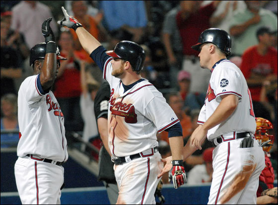 Atlanta Braves' Brian McCann, center, celebrates with Edgar Renteria, left, and Chipper Jones after McCann hit a three-run home run against the Boston Red Sox during the fifth inning of a Major League Baseball game Monday, June 18, 2007, at Turner Field in Atlanta. 