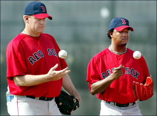2.24.04: Red Sox pitcher Curt Schilling (left), has been in camp for some time, but today he was joined by fellow ace righthander Pedro Martinez (right) who worked out for the first time at the team's minor league facility. They are shown tossing baseballs, biding their time on the pitching mound, while listening to a coach go over some details before a morning drill.