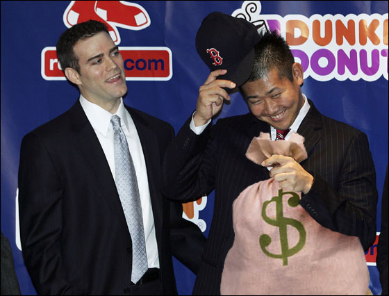 Daisuke Matsuzaka (R) hesitates before he tries on his hat as Red Sox general manager Theo Epstein looks on during a press conference announcing that the pitcher has signed with the Boston Red Sox on December 14, 2006 at Fenway Park in Boston, Massachusetts. Matsuzaka will earn $52 million over six years.