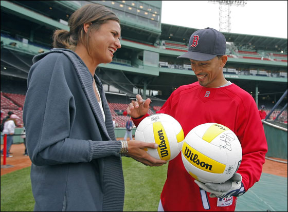 Professional volleyball player Logan Tom gets a couple of autographs on a pair of volleyballs from Red Sox shortstop Julio Lugo during batting practice at Fenway Park.