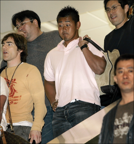 Boston Red Sox pitcher Daisuke Matsuzaka, in pink shirt holding bag over shoulder, arrives at Tampa International Airport, Monday, Feb. 12, 2007, in Tampa, Fla.