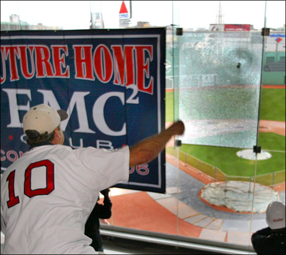 A pane of glass is shattered by a concrete baseball thrown by Dave Hixson from Hudson,on the tempered glass enclosure that  encloses the elevated Fenway Park .406 Club, as Red Sox President/CEO Larry Lucchino looks on. Hixson, an EMC employee was chosen for the honor, as he fired a pitch into the windshield-like glass, as it shattered. The glass will be coming down as the .406 Club will be converted into anew, open-air seating area called the EMC Club. The .406 Club is named after Red Sox legend, Ted Williams, and his batting average. The new EMC Club will be at the suite level, and will have exactly 406 seats.