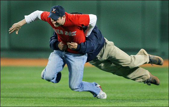 A Fenway Park security official makes a great open field tackle, as he brings down a fan who ran into the outfield during the ninth inning of Boston's 9-1 victory over Tampa Bay. The man was escorted off the field and lead away to jail no doubt.