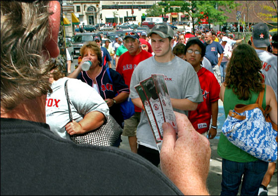 A scalper holds up Red Sox tickets as he walks down Brookline Ave. towards Kenmore Square 30 minutes before a Red Sox-Yankees game