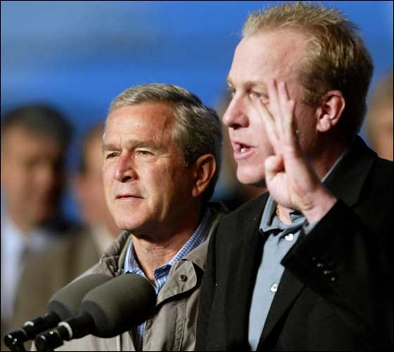 11.1.04: US President George W. Bush (left) listens to World Series Championship Boston Red Sox pitcher Curt Schilling as he introduces him to the crowd during a campaign rally at ABX Air Hangar 01 November 2004