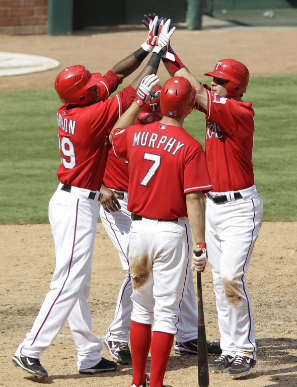 David Murphy, Julio Borbon, left, and Elvis Andrus, rear, congratulate Michael Young, right, on his three-run home run off of  Manny DelTimlin in the seventh inning of a baseball game Sunday, Aug. 15, 2010, in Arlington, Texas. The Rangers won 7-3.