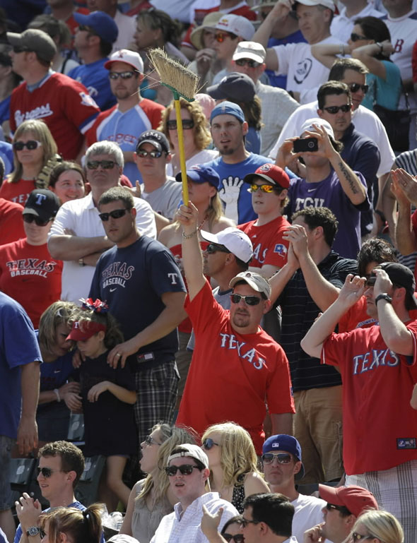 A fan waves a broom as others stand in the closing minutes of an MLB baseball game between the Boston Red Sox and the Texas Rangers on Sunday, April 3, 2011, in Arlington, Texas. The Rangers won 5-1, sweeping the Red Sox in the Rangers' weekend season opener.