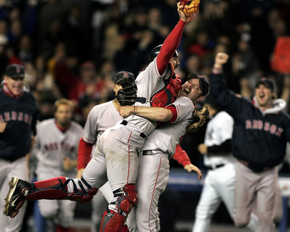 Red Sox catcher Jason Varitek and pitcher Alan Embree embrace as the rest of the Boston players rush out of the Yankee Stadium dugout to begin the celebration following the final out of the Game Seven 