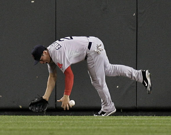 Boston Red Sox center fielder Jacoby Ellsbury falls to the ground after slamming into the fence trying to catch a ball hit by Robert Andino of the Baltimore Orioles in the sixth inning of their MLB American League baseball game in Baltimore, Maryland September 26, 2011. Andino was credited with a three-run inside the park home run.